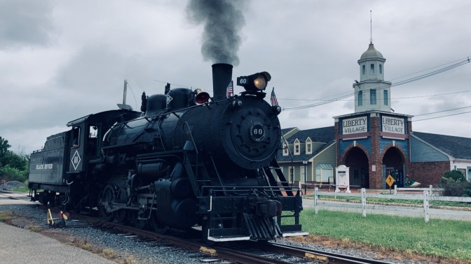 Steam locomotive on tracks approaching station.