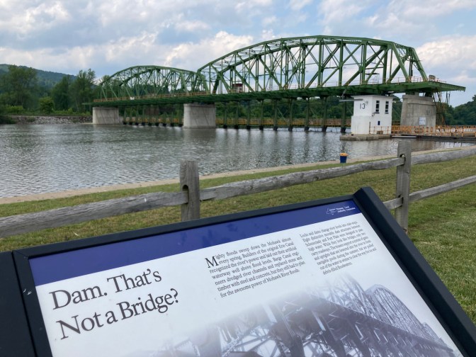 Canal dam, with sign in foreground that says DAM THAT'S NOT A BRIDGE.