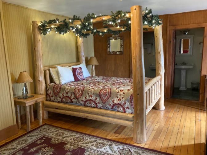 Rough-hewn bed four-poster bed, with Christmas light on top of bed.