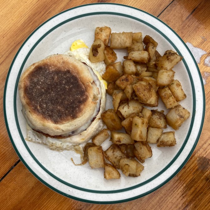Egg sandwich on an English muffin, with home fries.