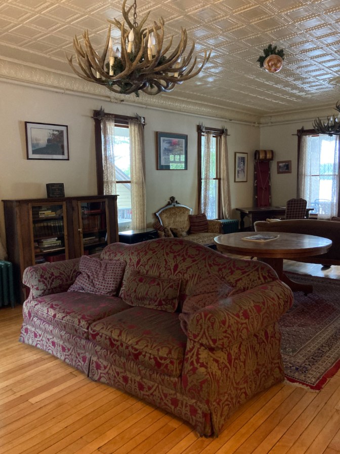 Great Room parlor with sofa in middle of floor, intricate plaster work in ceiling, and deer antler chandelier.