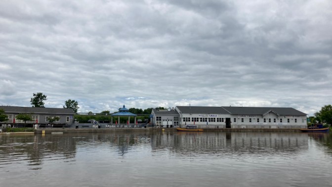 Waterfront of Herkimer along Mohawk River, with pier and buildings for Erie Canal Cruises.