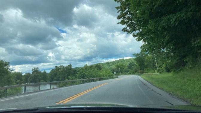 View of Route 28 in New York, with hills and trees on one side, and river on other.