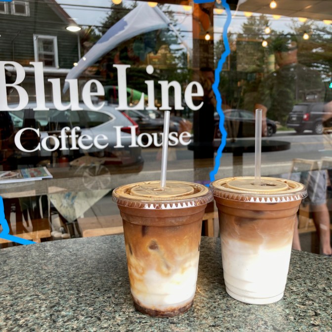 Two lattes on table outside window of Blue Line Coffee House.