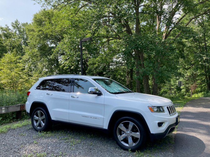 2014 Jeep Grand Cherokee, in white, parked on gravel strip.