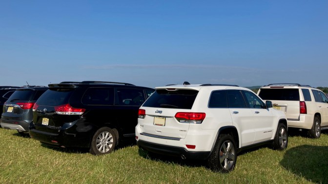 White Jeep Grand Cherokee parked in field.