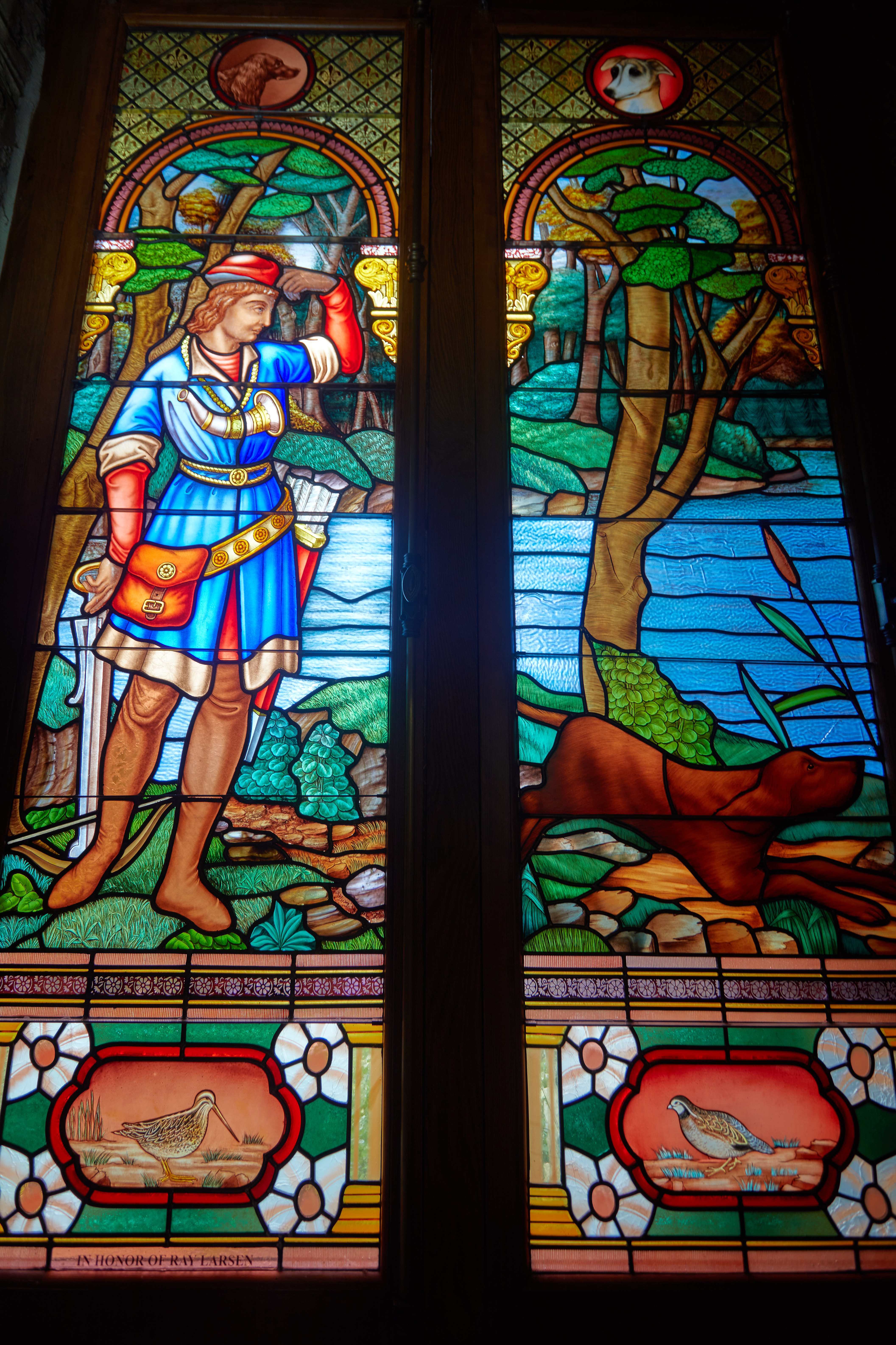 Stained glass window of St. Hubert with a dog.