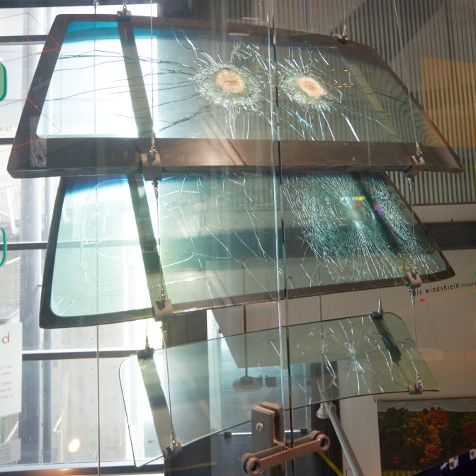 Three cracked windshields, hanging from the ceiling.