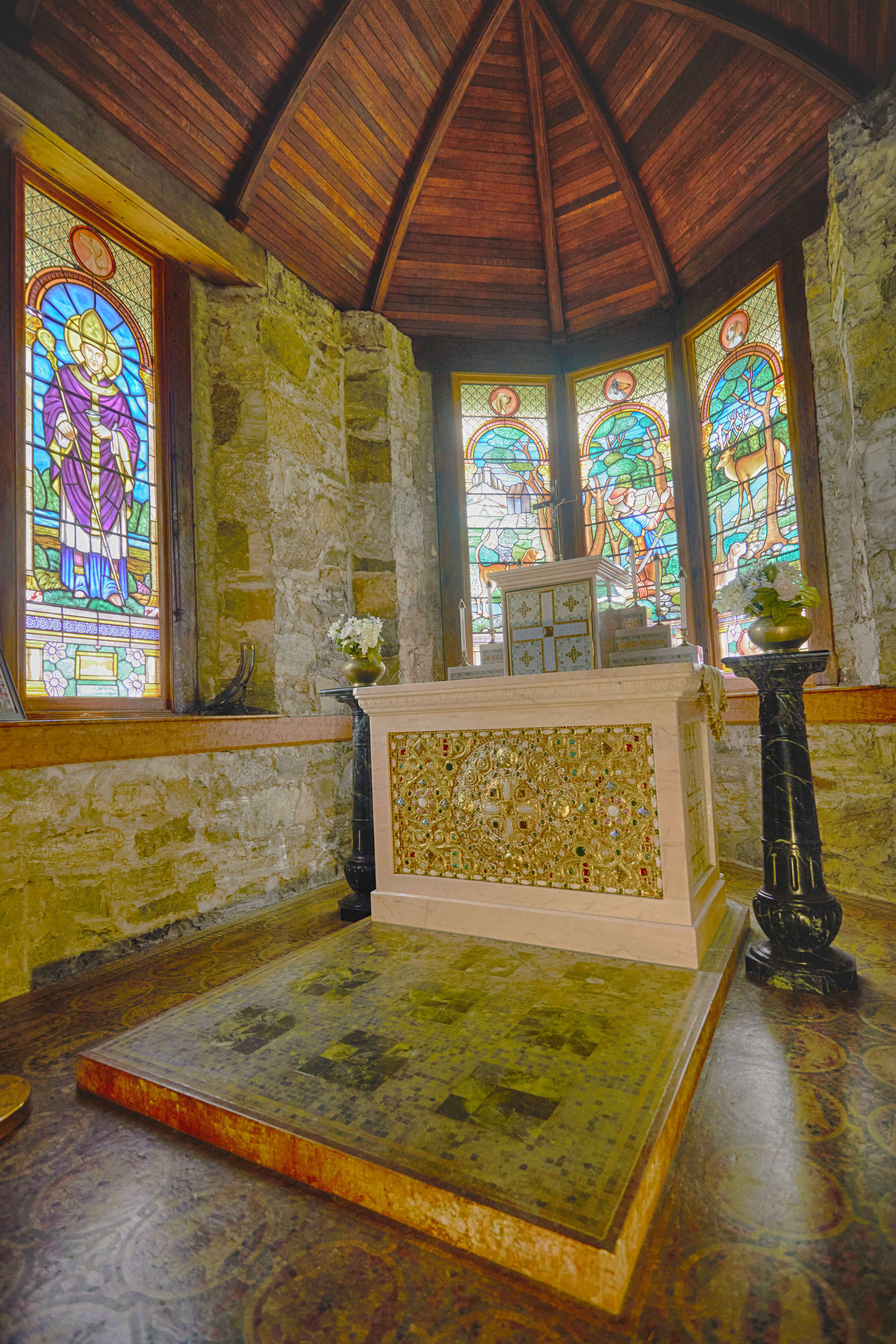 Altar and stained glass windows at front of church.