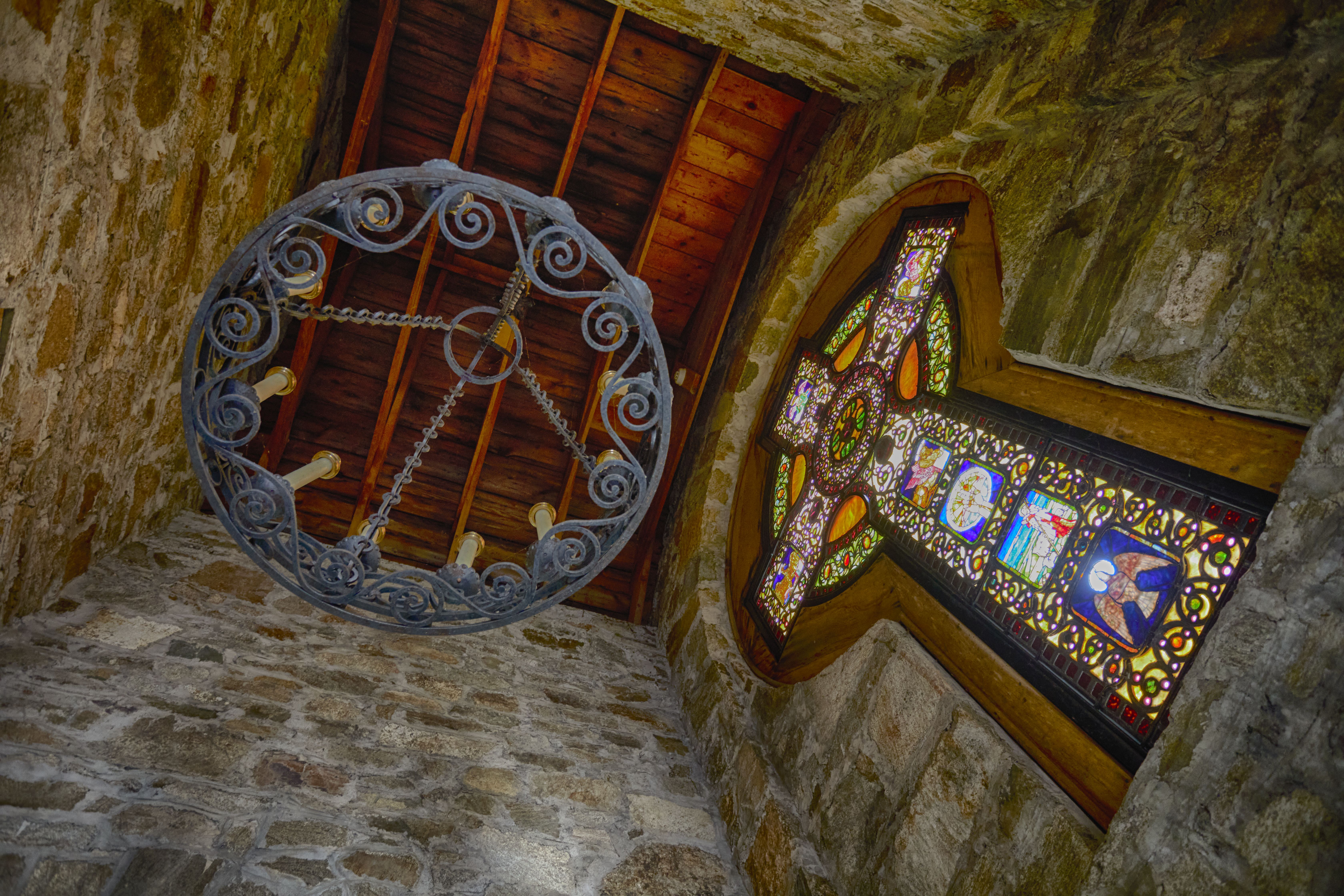 Chandelier hanging from ceiling, beside Celtic Cross. Scene is photographed looking upward.
