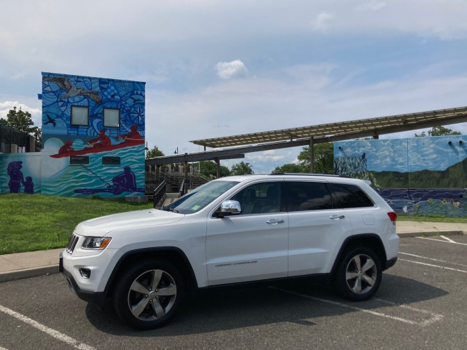 2014 Jeep Grand Cherokee parked in front of building with wall mural.