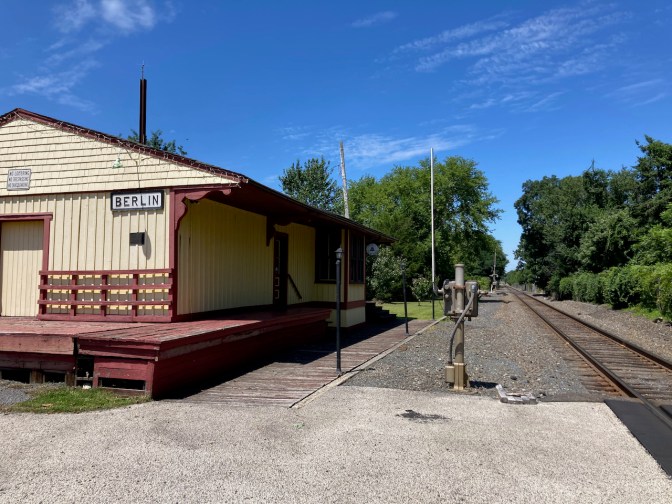 Long-A-Coming Depot beside train tracks.