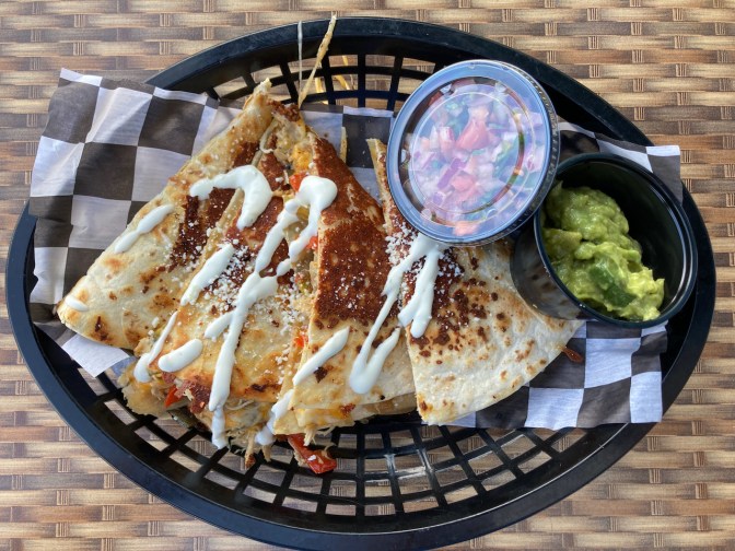 Quesadilla in basket, with sides of gaucamole and salsa.