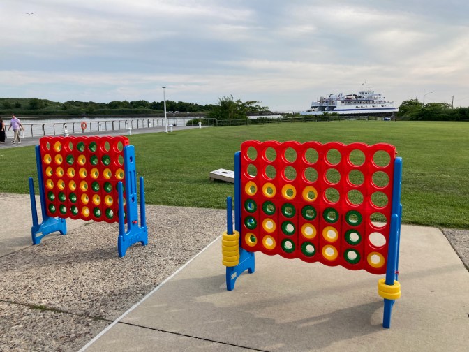 Life-size Connect Four games on patio, with ferry in distance.
