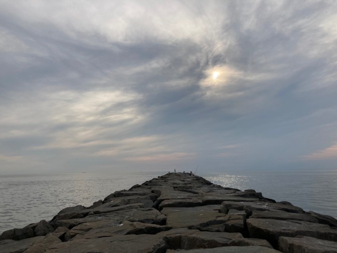View of jetty extending out into Delaware Bay, with cloudy sky.