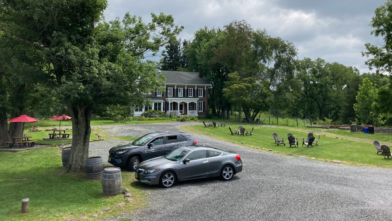 Gravel parking lot with 2012 Honda Accord coupe and Toyota SUV. A large mansion is on the other end of the lot.