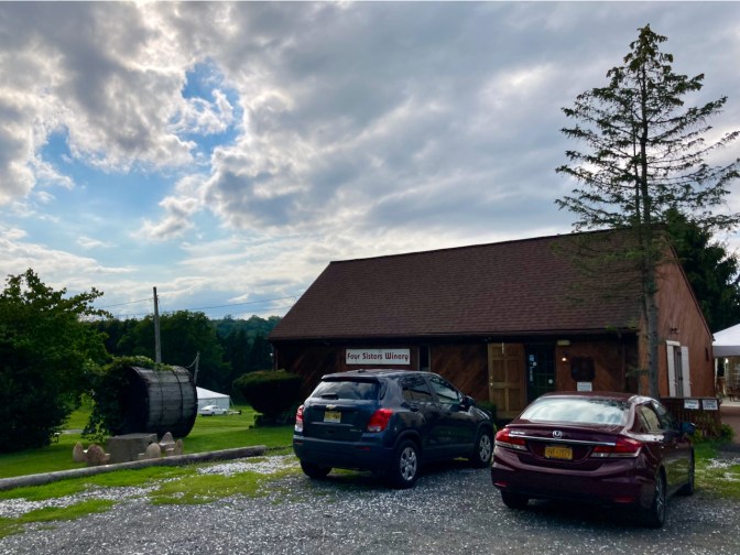 Tasting room of Four Sisters Winery, with cars parked in front of it.