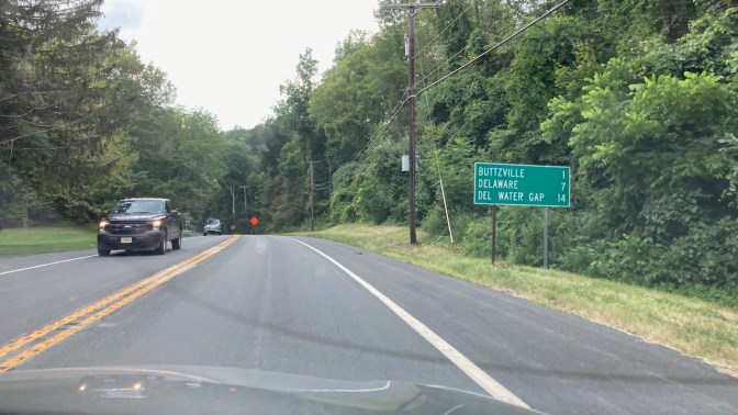 Sign along two-lane road that reads BUTTZVILLE 1, DELAWARE 7, DEL WATER GAP 14