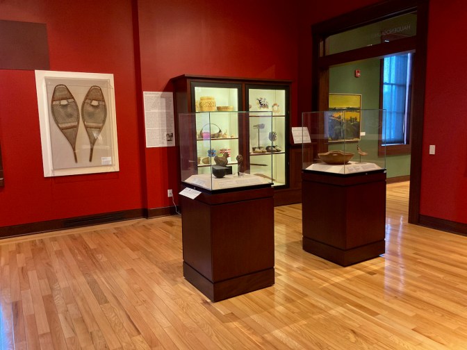 Gallery with Native American items, including baskets, jars, and snow shoes.