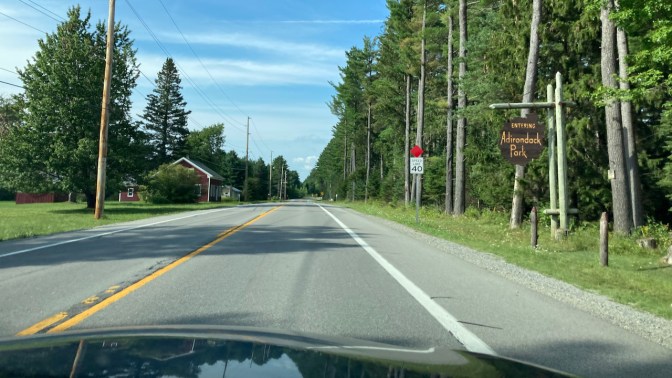 View of I-28, with sign on right saying ENTERING ADIRONDACK PARK.