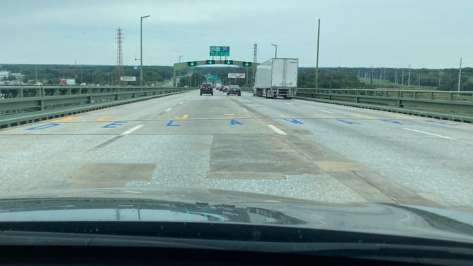 View of Delaware Memorial Bridge, with NEW JERSEY DELAWARE diving line on road surface.