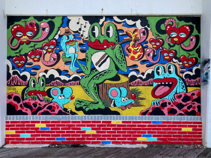 Mural of cartoon frogs and apples on wall.