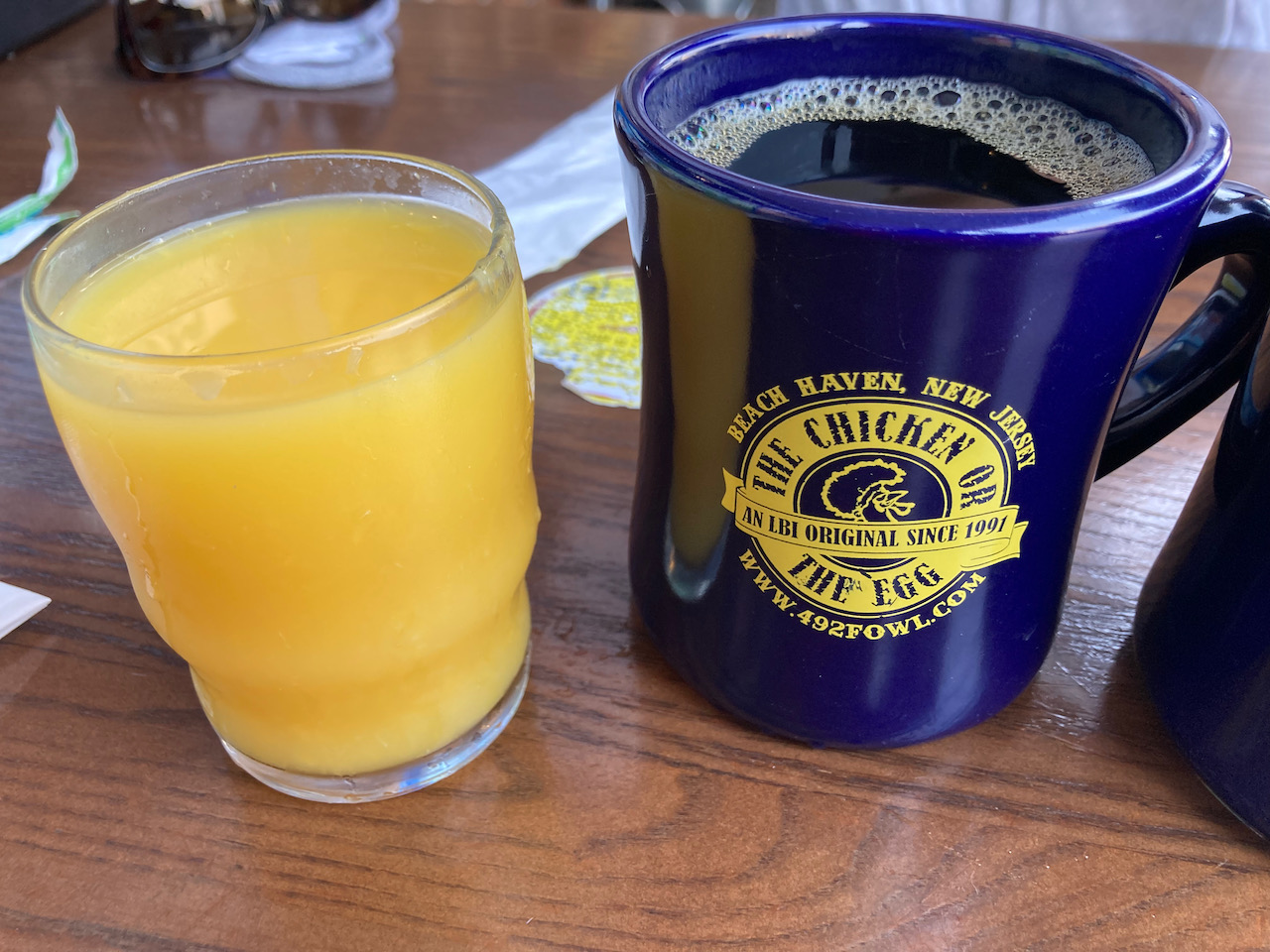 Glass of orange juice and cup of coffee on table.
