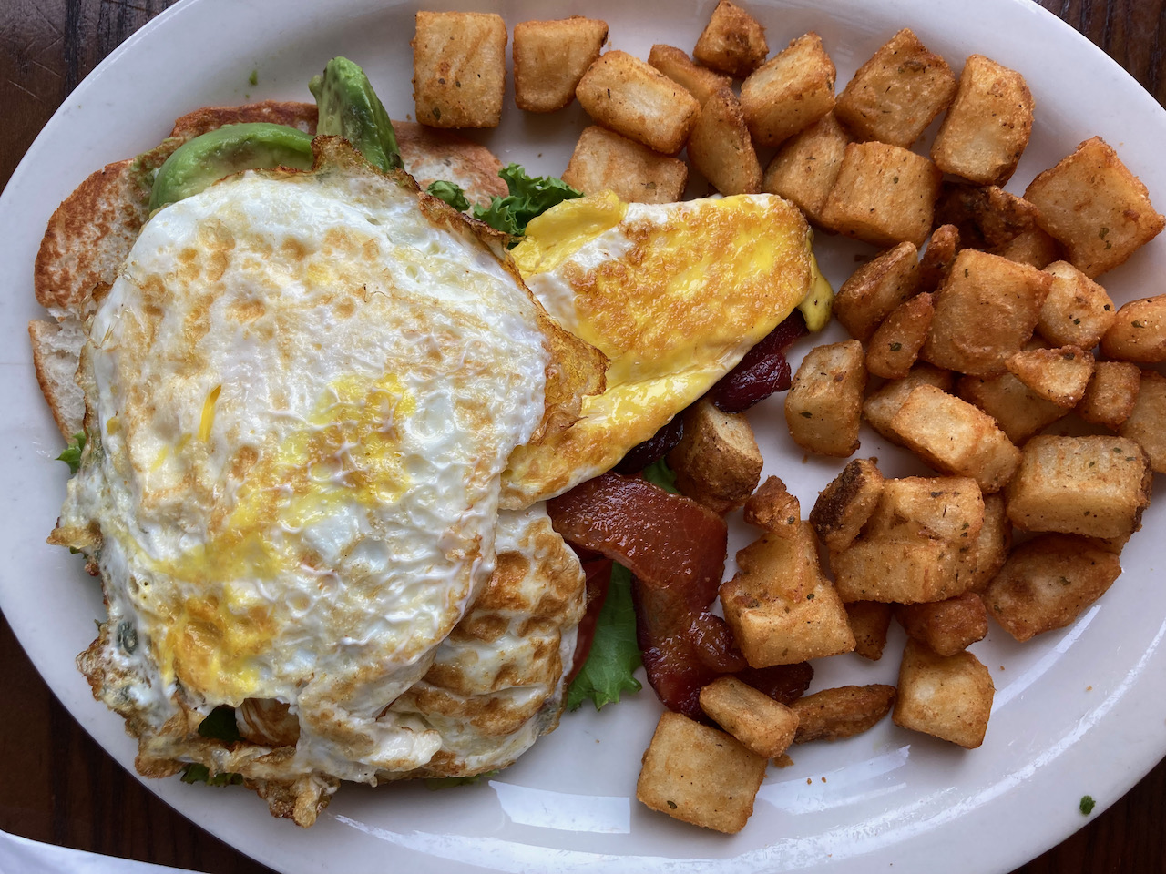 Egg and avocado on toast, with bacon and home fries.