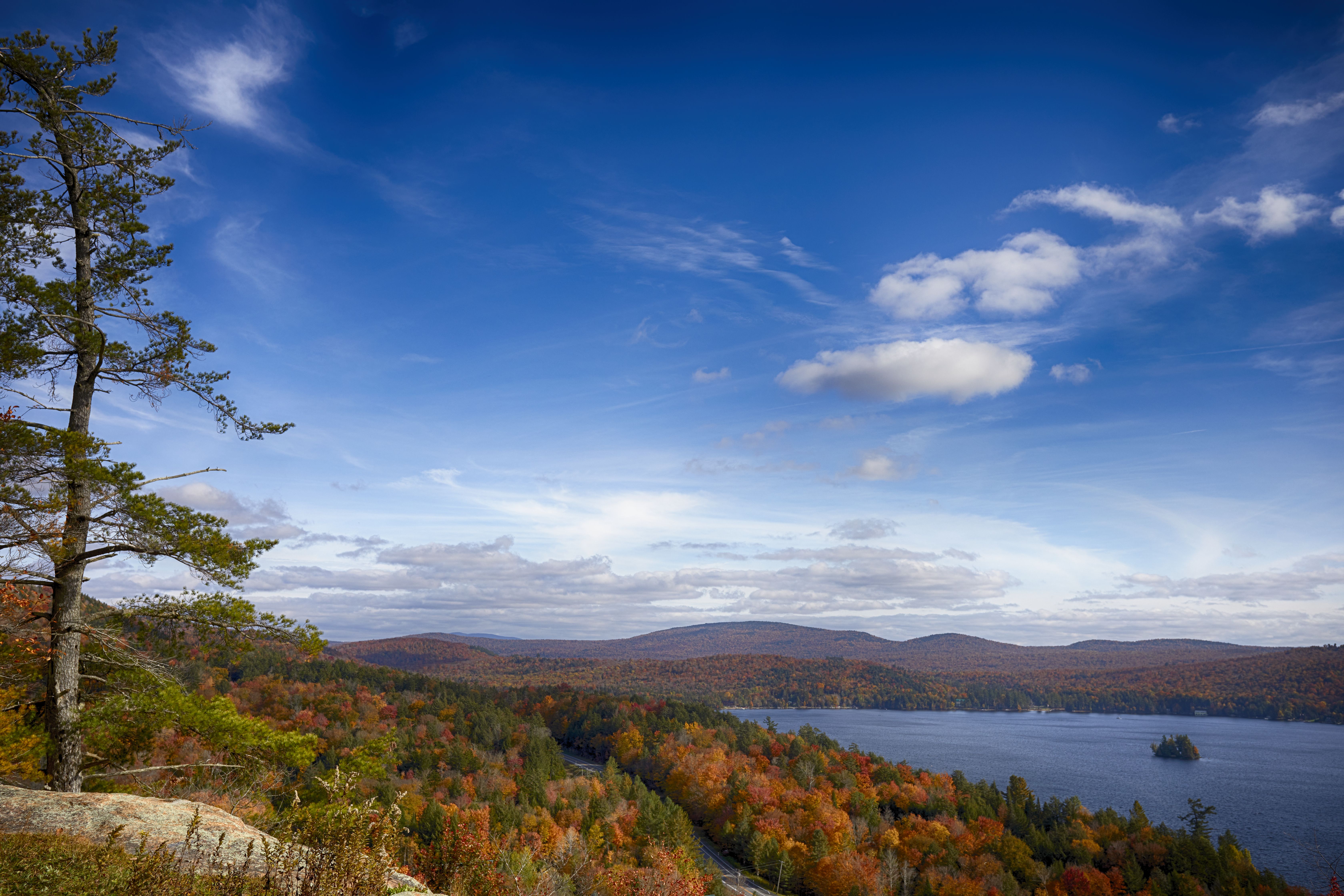 View of hillside, with trees covered in colored leaves, and Fourth Lake in distance.