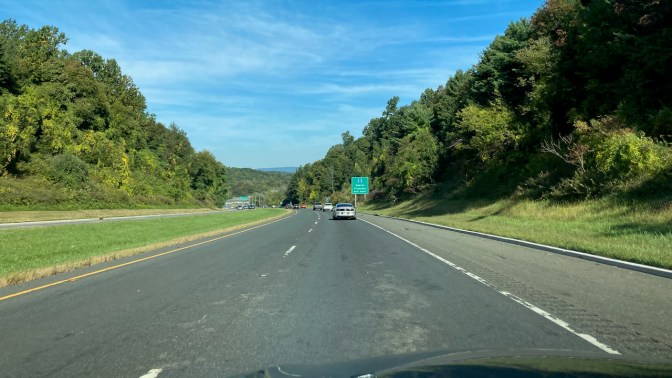 View of Route 23 northward. The road is tree-lined, and mountains are in the distance. 