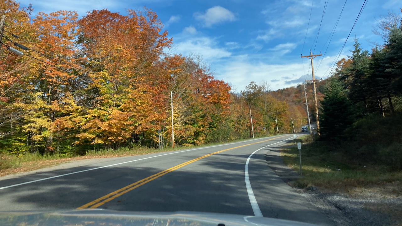 NY28 with red and orange trees along side of road. 