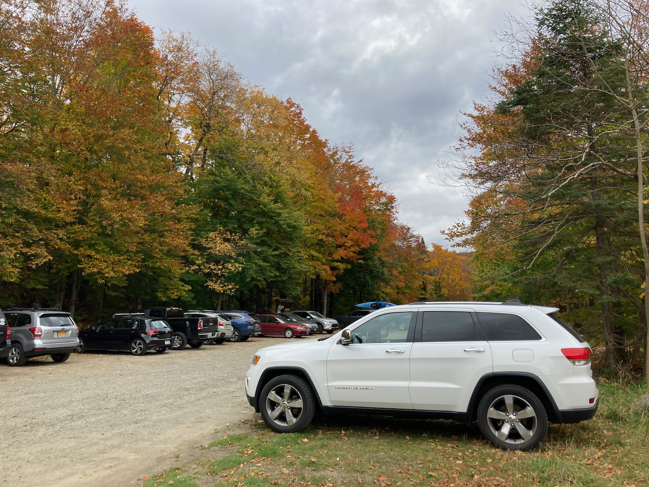 White Jeep Grand Cherokee, parked in dirt lot of Blue Mountain hiking trail. 
