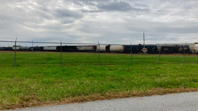 Train yard behind chain link fence. 