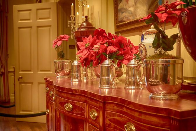 Sideboard with vases filled with knives, and silver tankards. 
