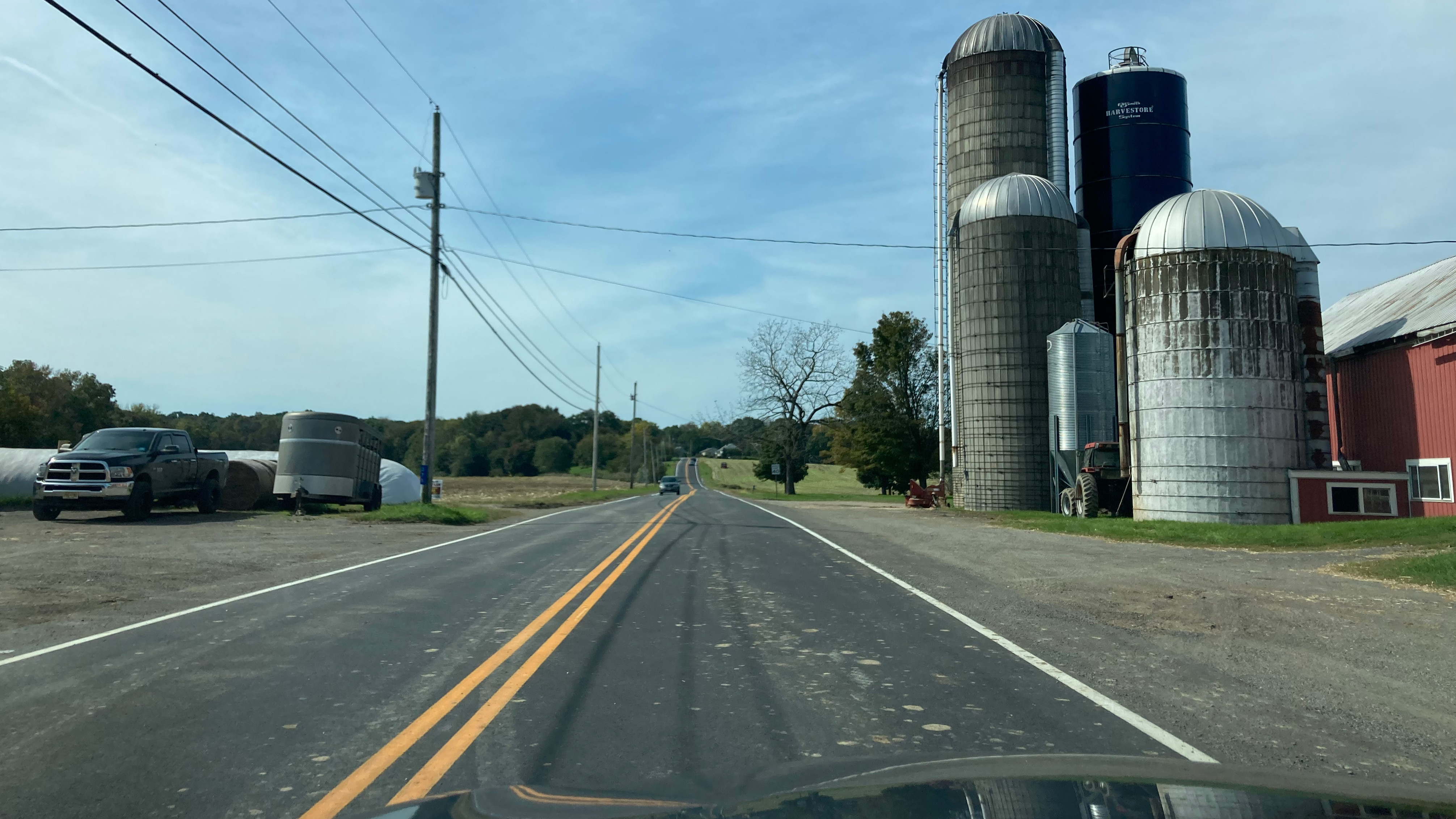 View of Route 519, with grain silos and barn on right side of road.