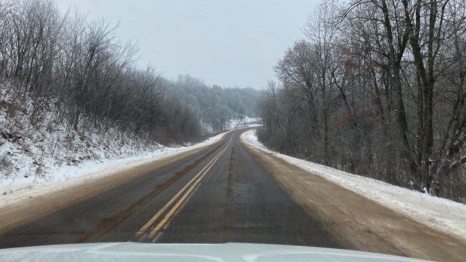 Two-lane road, with icy on trees and snow on ground.