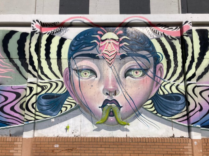 Mural of woman with forked tongue and butterfly wings.