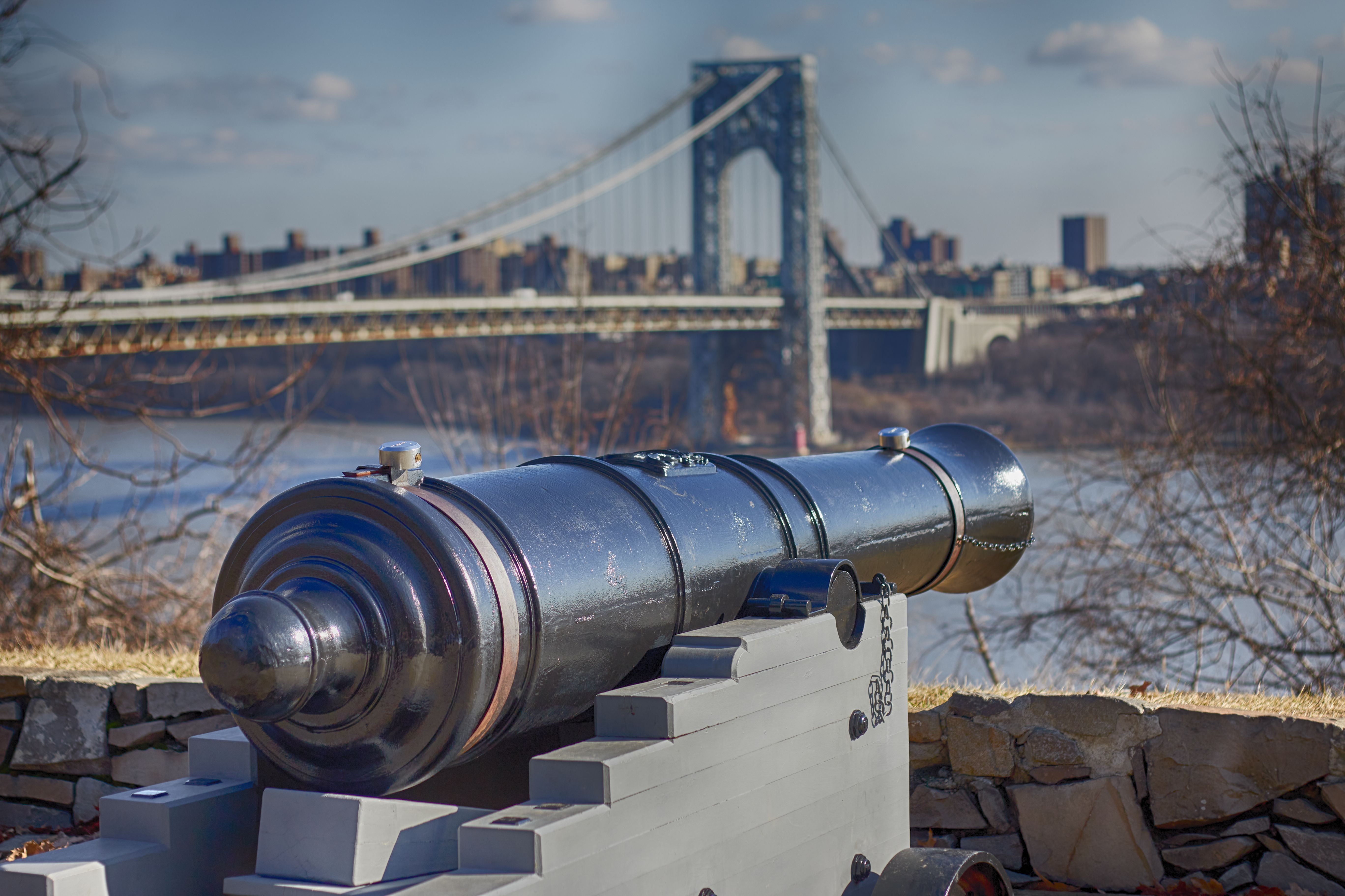 Cannon looking over river, with George Washington Bridge in background.