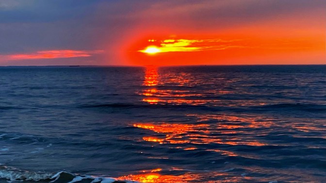 Sunset over ocean at beach.