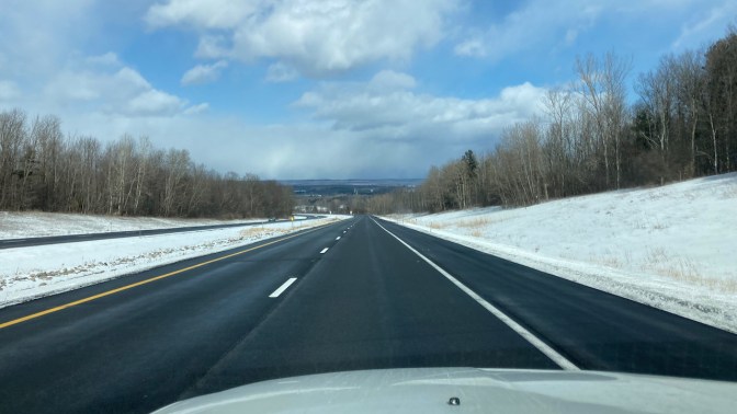Clear road, with snow on roadside, and blue skies above.