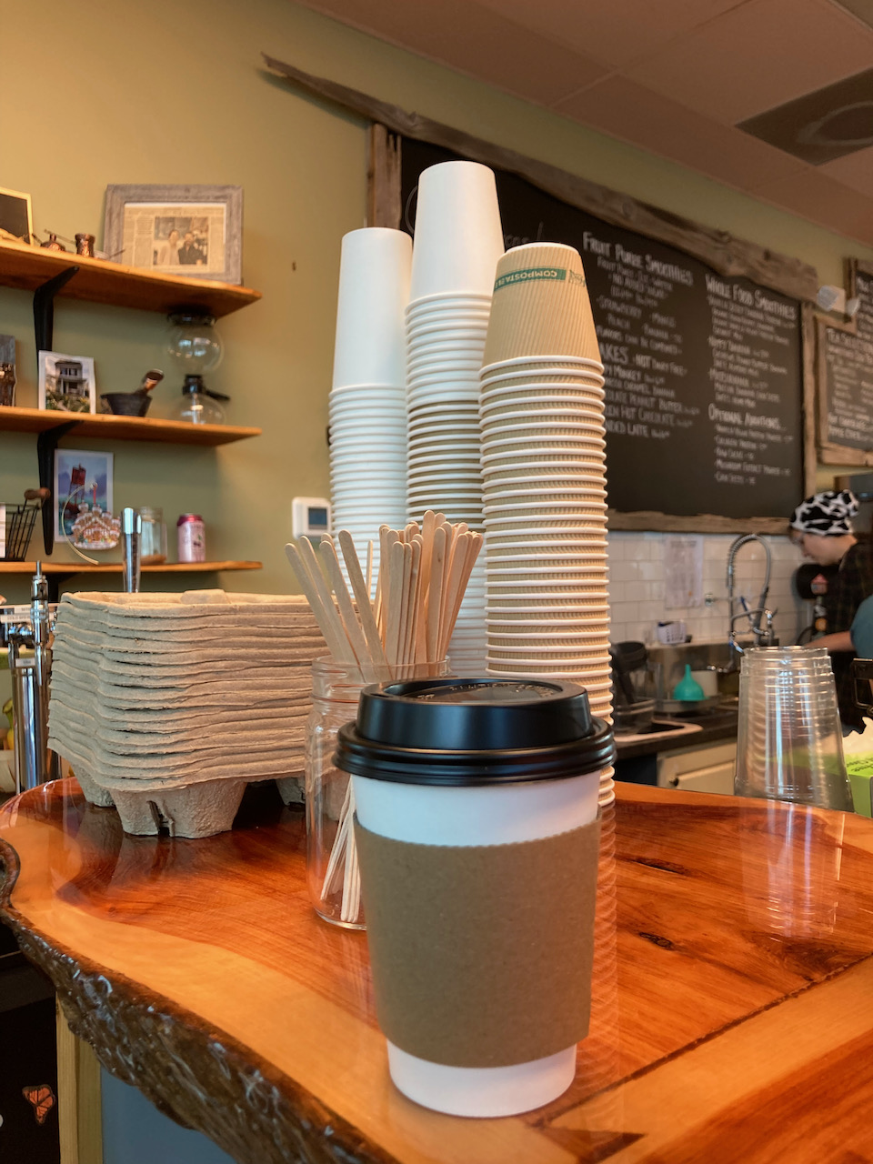 Coffee cup on counter, with chalkboard menu in background.