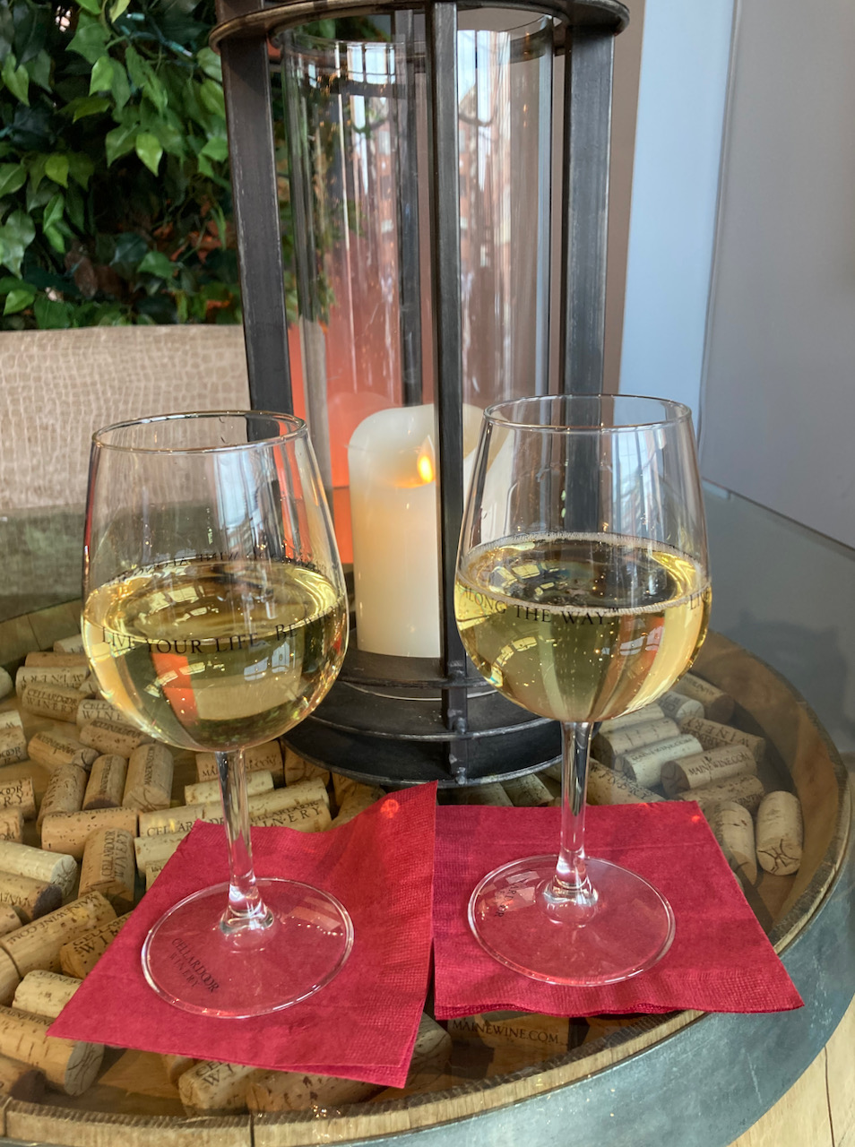 Two glasses of white wine on table, with candle in background.