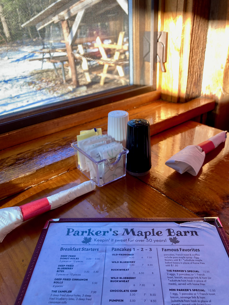 Menu on table at Parkers Maple Barn, with view outside window of outdoor eating area.