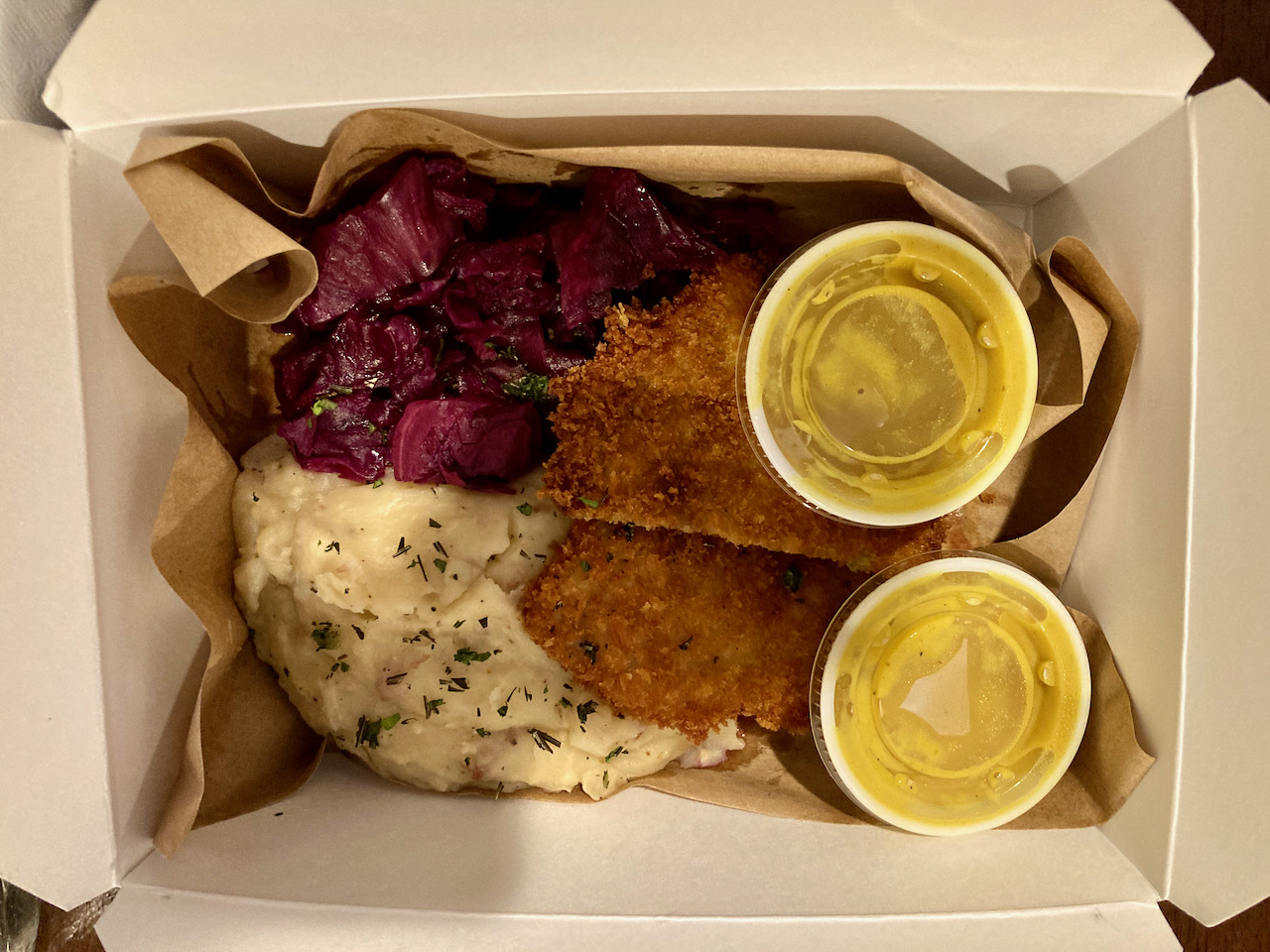 Pork schnitzel, mashed potatoes and cabbage in container.