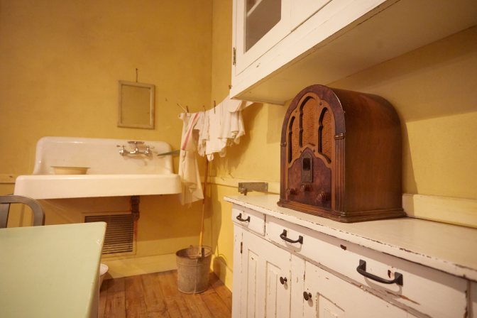 Small radio on top of cabinet in reproduction of family kitchen.