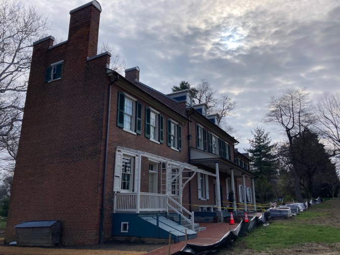 Exterior of rear of Wheatland, which includes caution tape, fencing, and piled bricks.