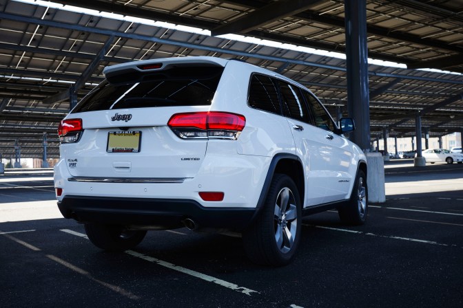 2014 Jeep Grand Cherokee parked under solar panels in parking lot.