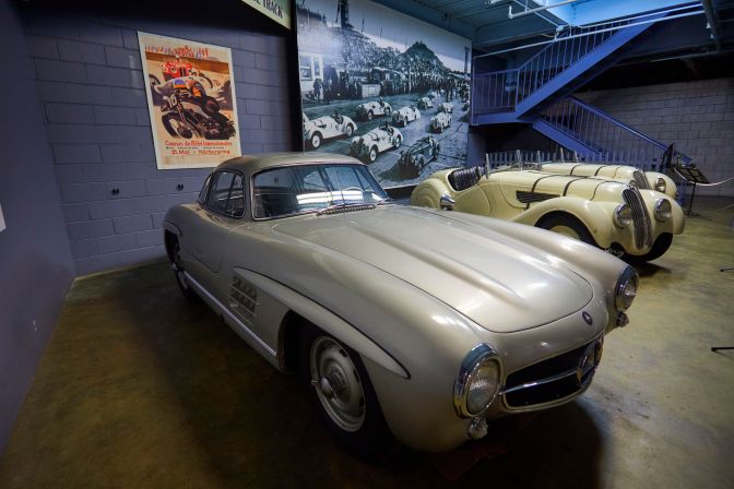 1955 Mercedes-Benz 300SL Gull Wing and 1937 BMW 328 in front of display about Nurburgring race track.