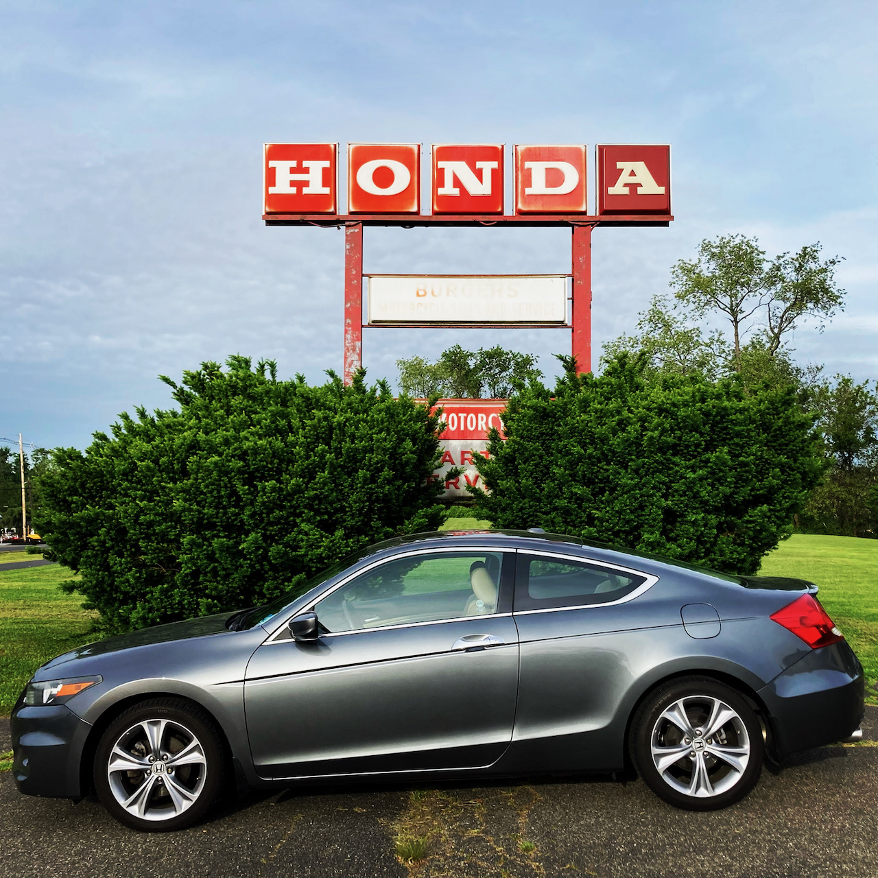 2012 Honda Accord coupe parked in front of red HONDA sign.