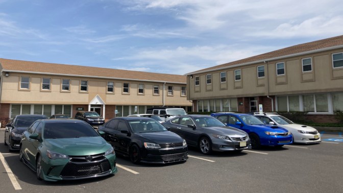 Parking lot with several modified cars in a row, and a 2012 Honda Accord in the middle.